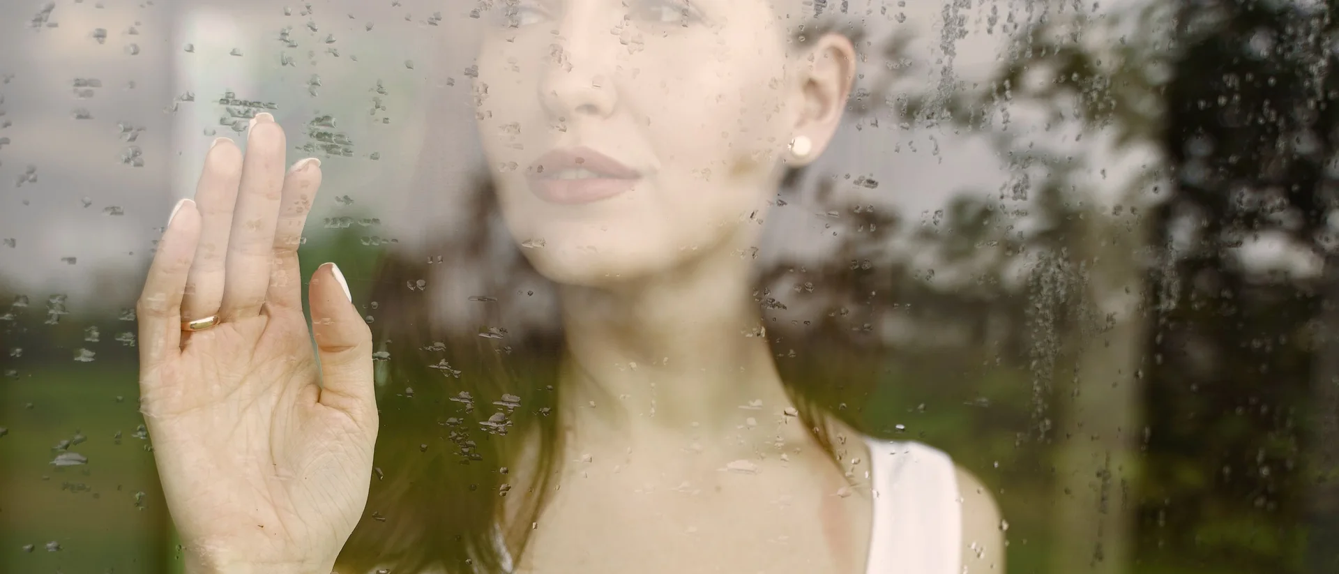 Woman reflecting beside the window of a rented flat after an unexplained change in her menstrual cycle